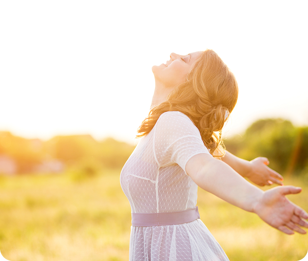 Woman embracing sunlight in open field.